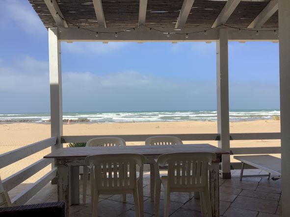 Blick auf Strand und Meer von Terrasse mit Esstisch und  vier Stühlen