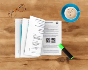 Die Anleitung zur Beseitigung deines Aufgabenchaos liegt offen aufgeschlagen auf einem Schreibtisch. Oben rechts daneben steht eine blaue Kaffeetasse, unten rechts liegt ein grüner Textmarker. Oben links liegt eine Brille.